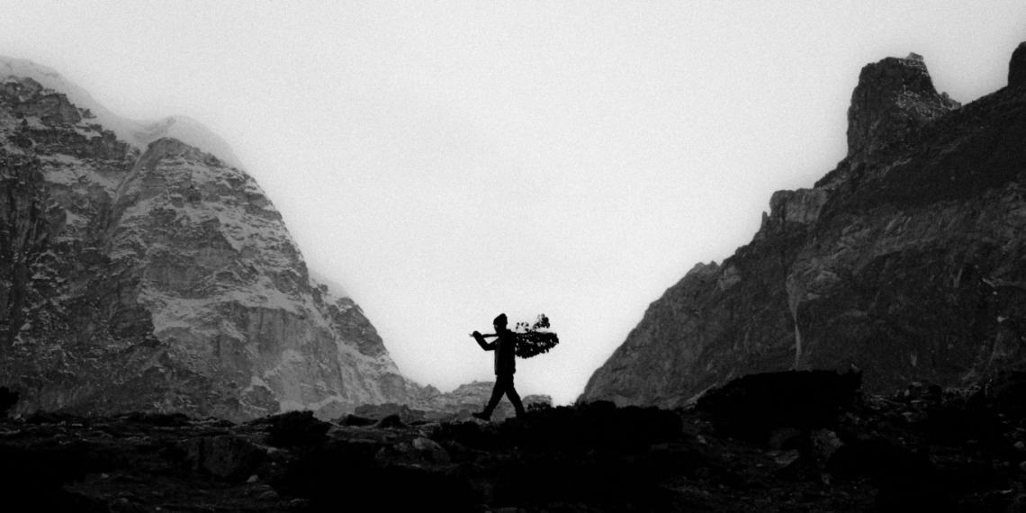 Silhouette of Sherpa in a rugged mountain landscape.